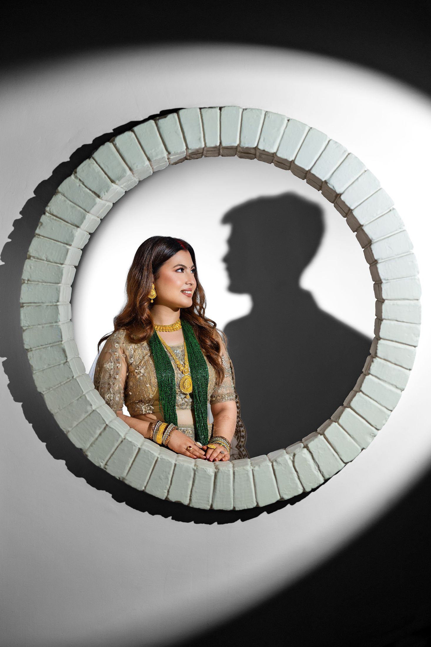 Artistic circular-frame portrait of Inusha in a gold and green traditional outfit beside Prashid's silhouette