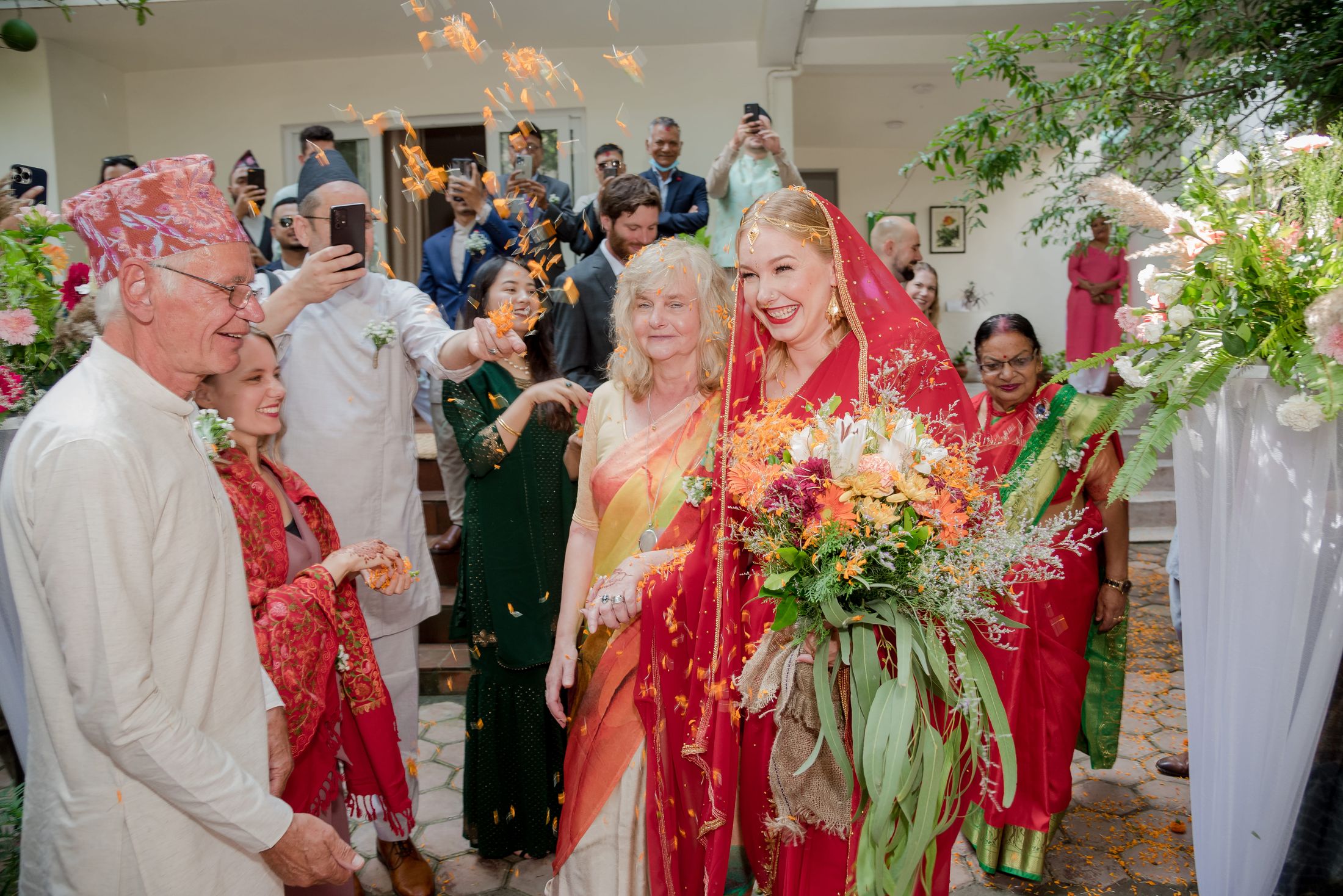 Jana arriving as the bride in a red saree with a bouquet, greeted by family members