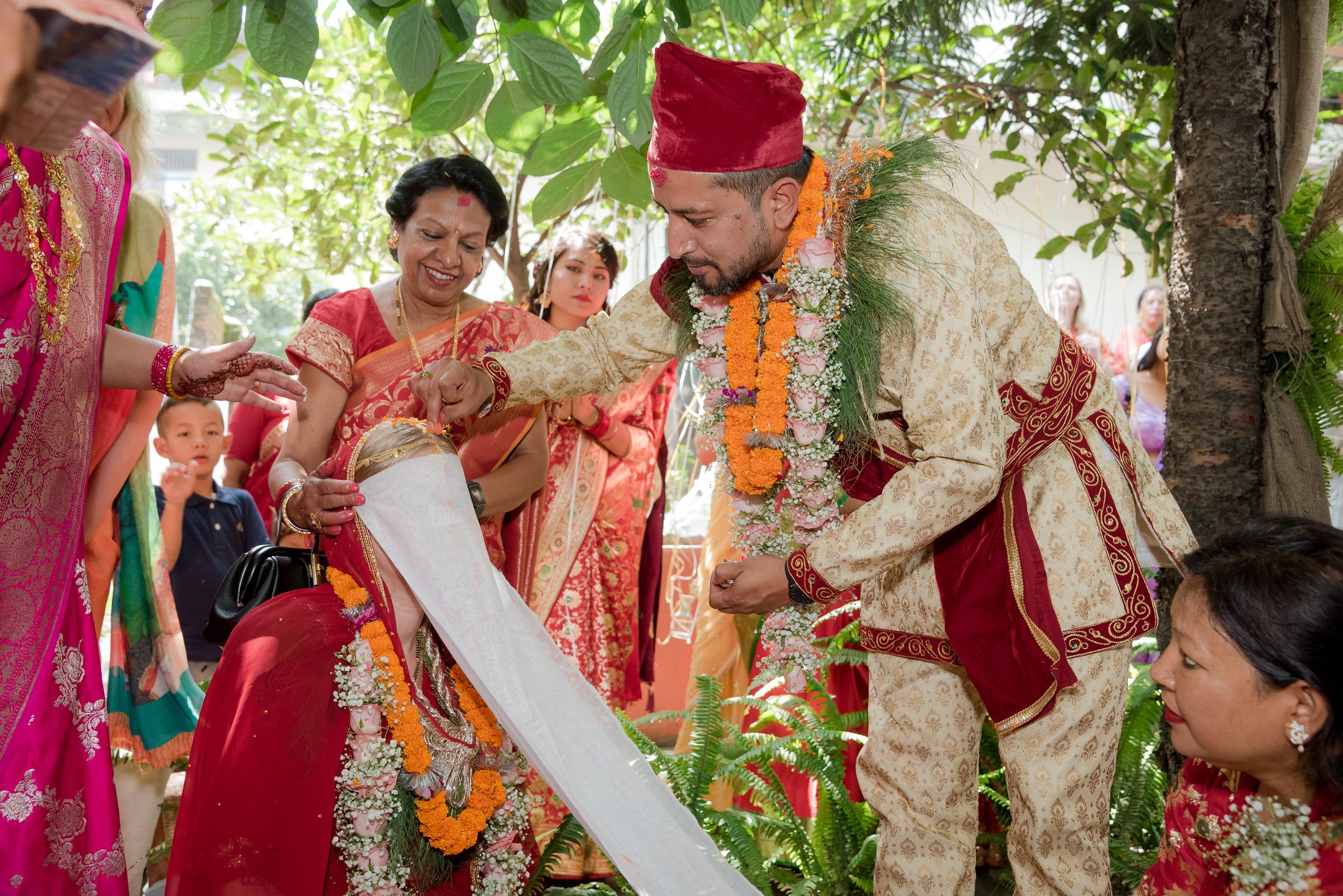 Family members blessing Raymon with a garland as a child looks on nearby