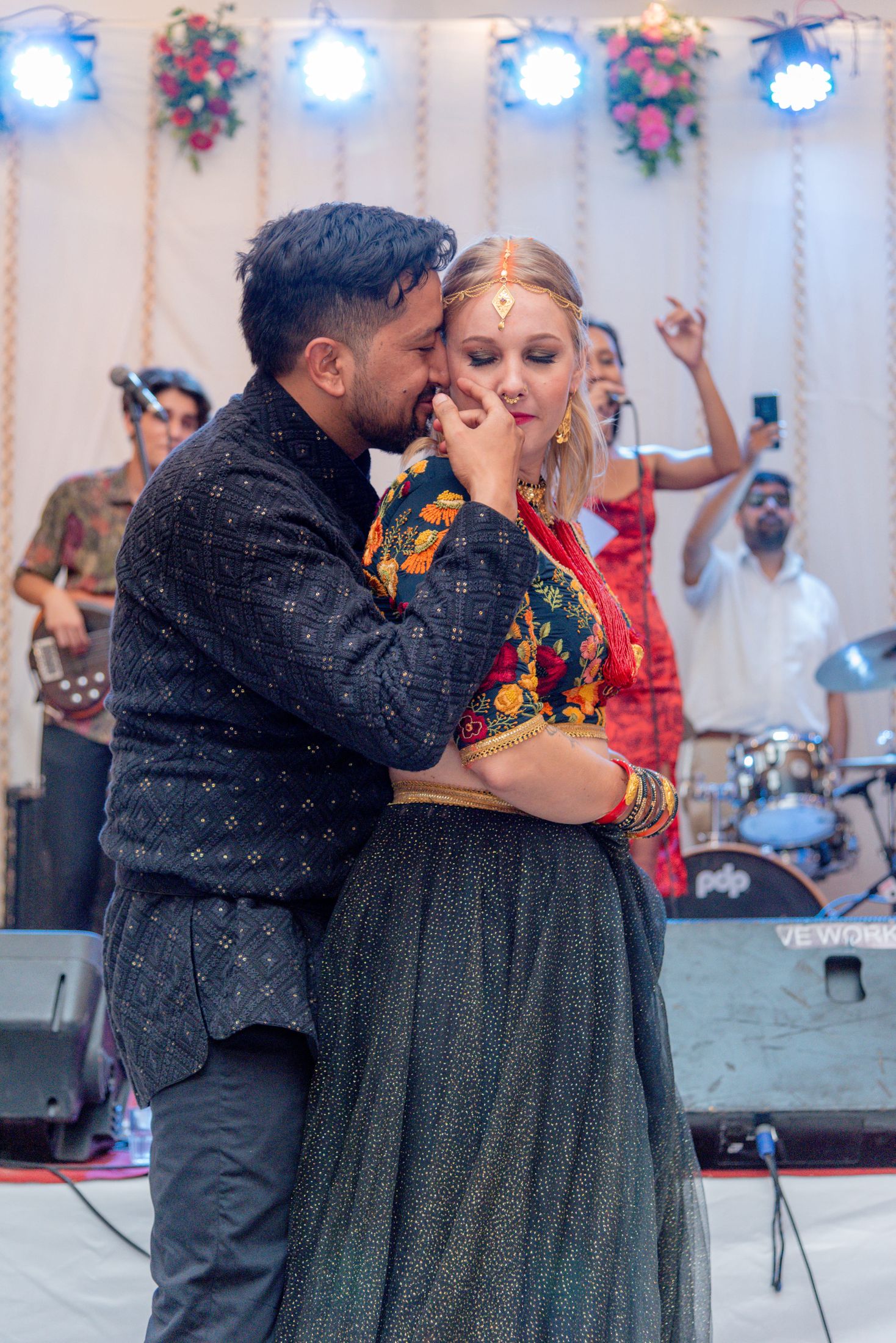 Raymon and Jana sharing a tender moment on stage with a live band performing behind them