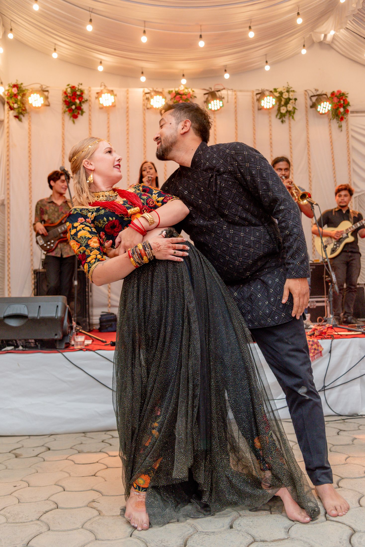 Jana and Raymon dancing together on stage under string lights