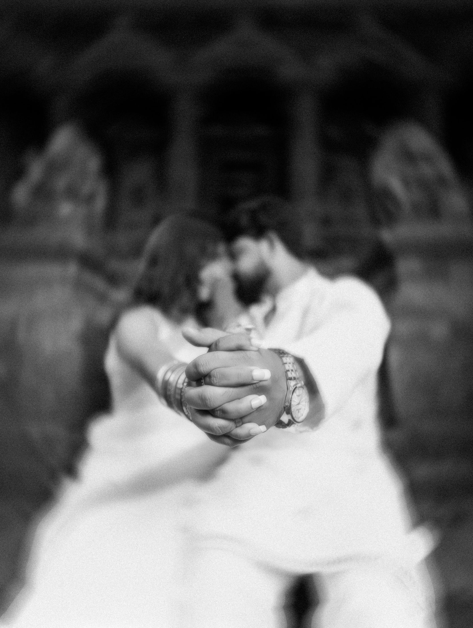 Black and white close-up of the couple's joined hands showing their wedding rings