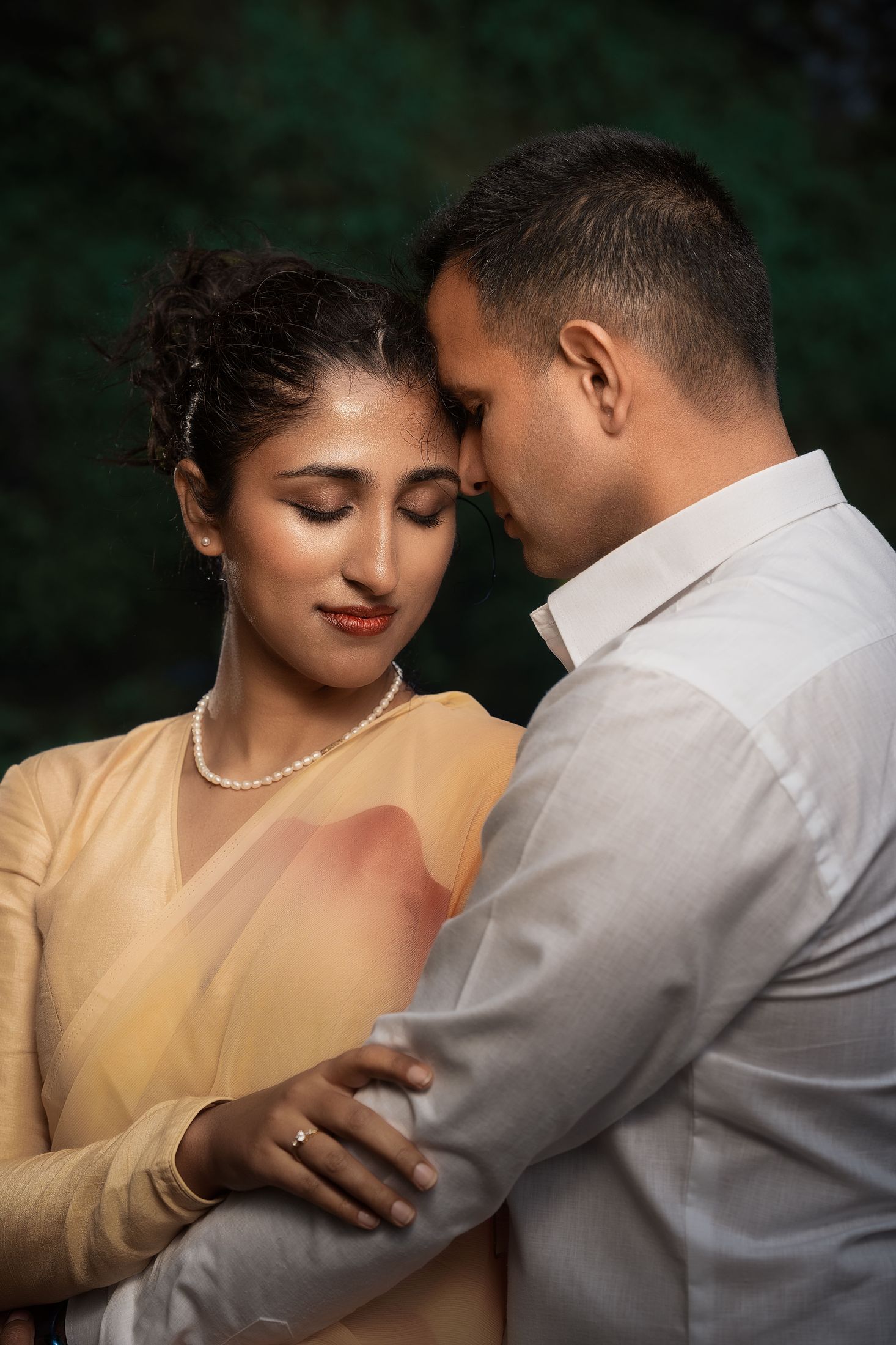 Disuja and Krishna in a close embrace, she in a beige and gold saree, foreheads touching