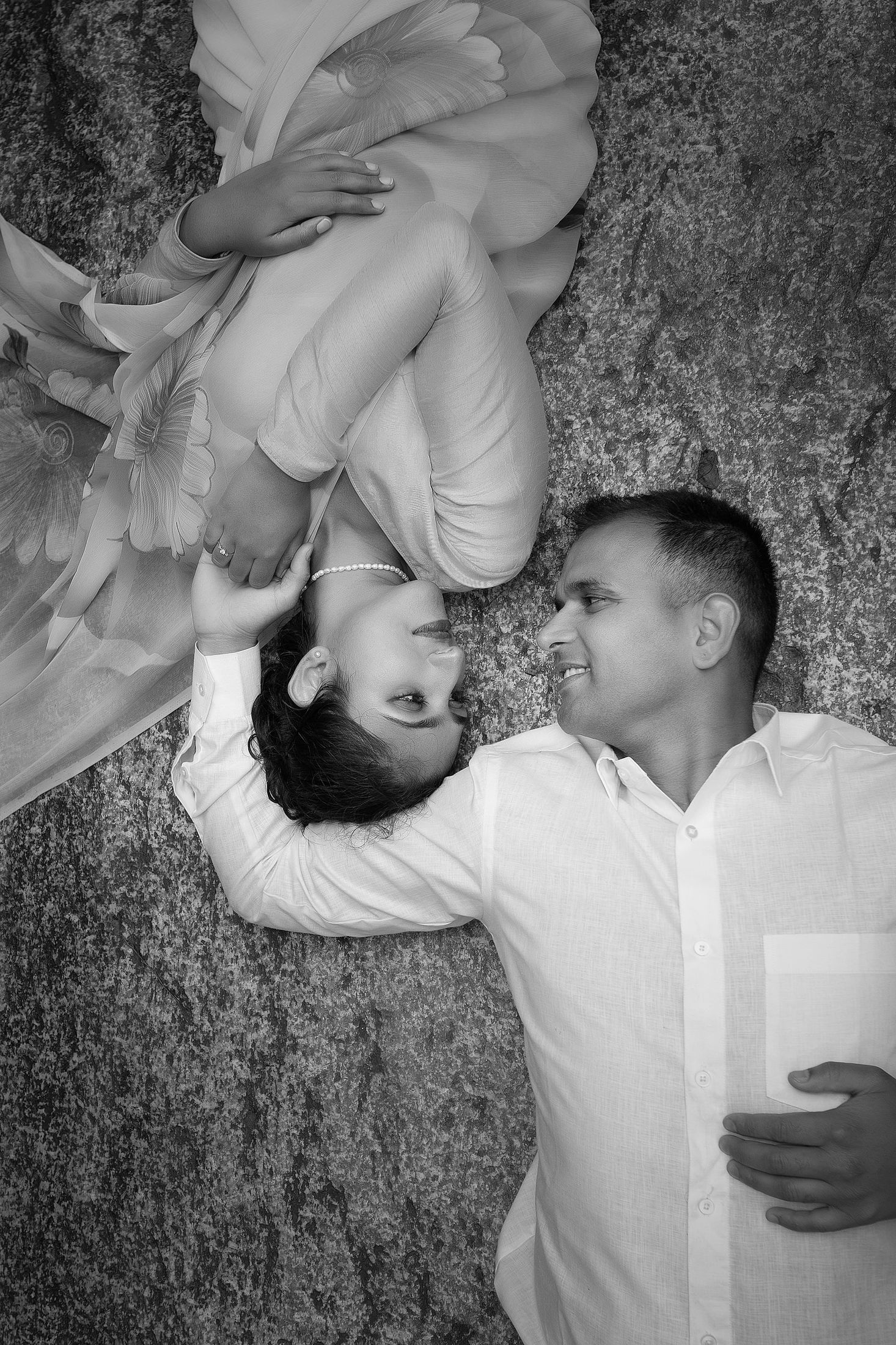 Black and white artistic portrait of Krishna lifting Disuja against a rocky wall