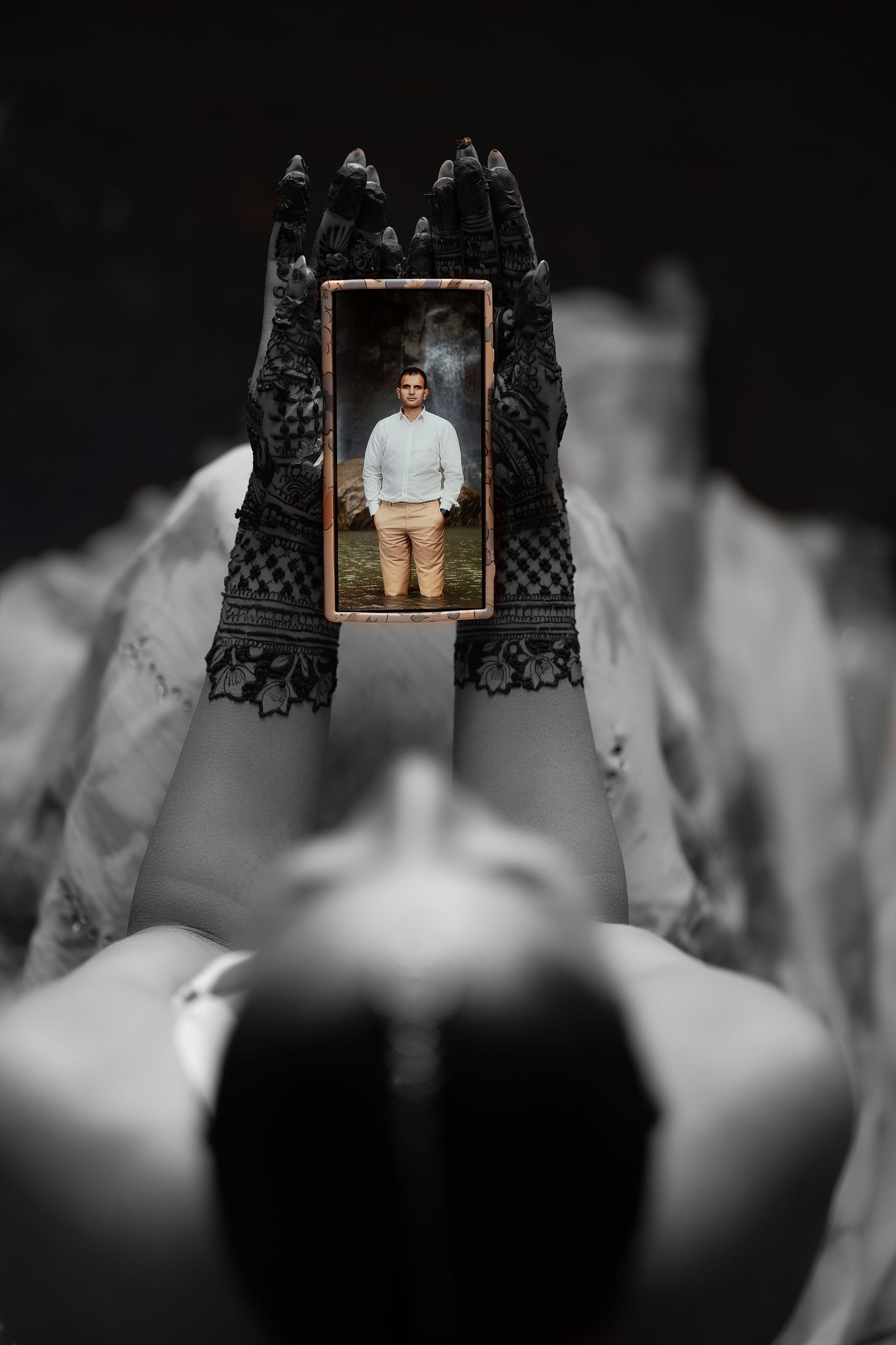 Artistic black and white composite of hands holding a small framed photo of Krishna above Disuja's silhouette