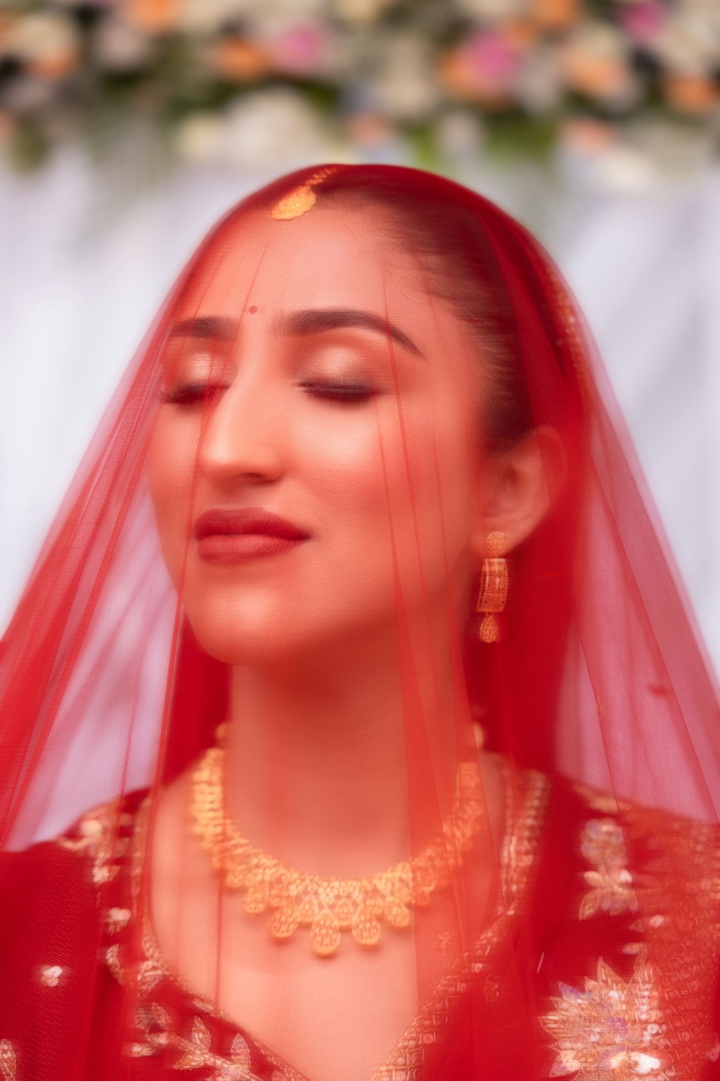 Disuja in a red bridal veil with eyes closed in an emotional moment