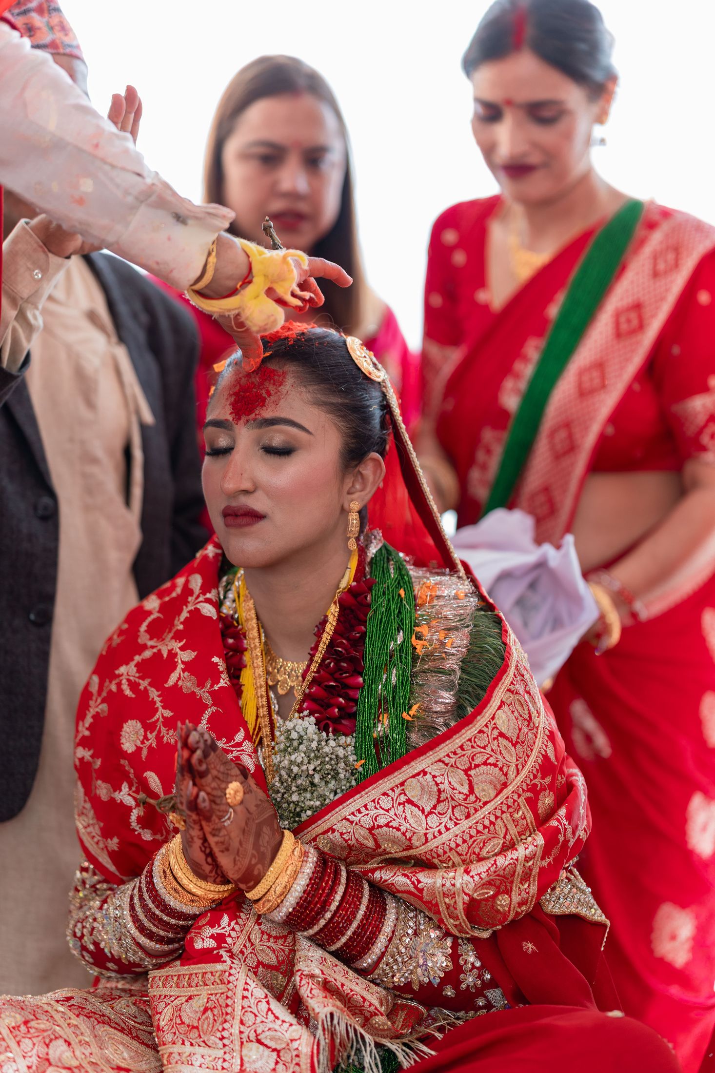 Disuja with hands folded in a blessing pose as tikka is applied to her forehead