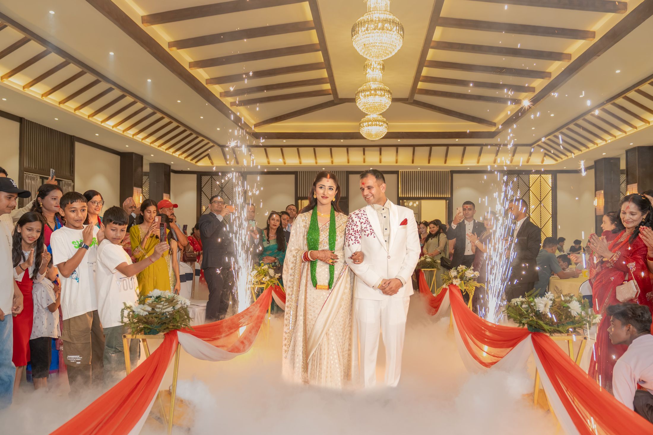 Couple walking down the reception aisle between cold spark fountains in a grand hall