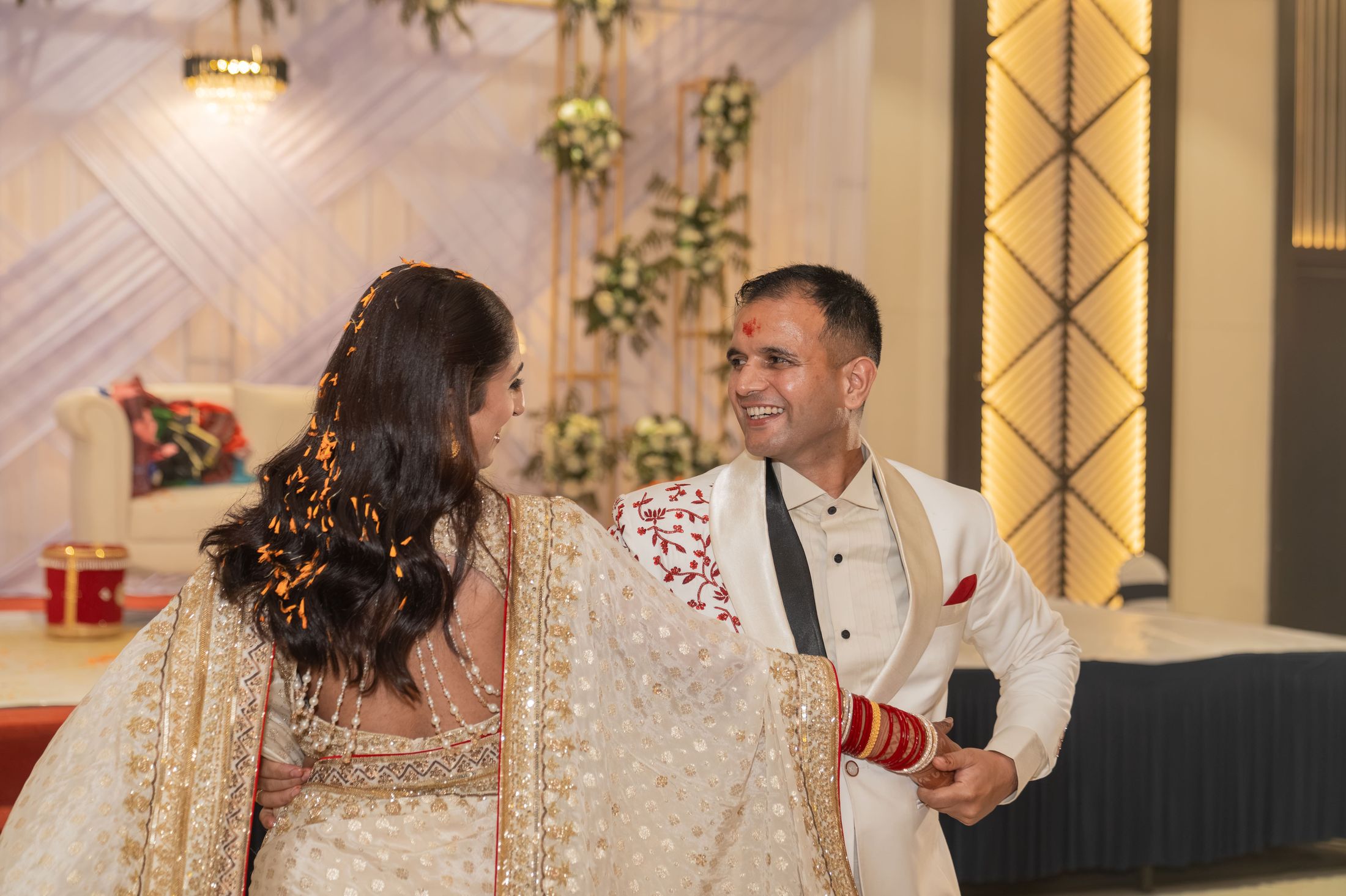 Reception moment with Disuja in a gold lehenga looking up at Krishna in a white sherwani
