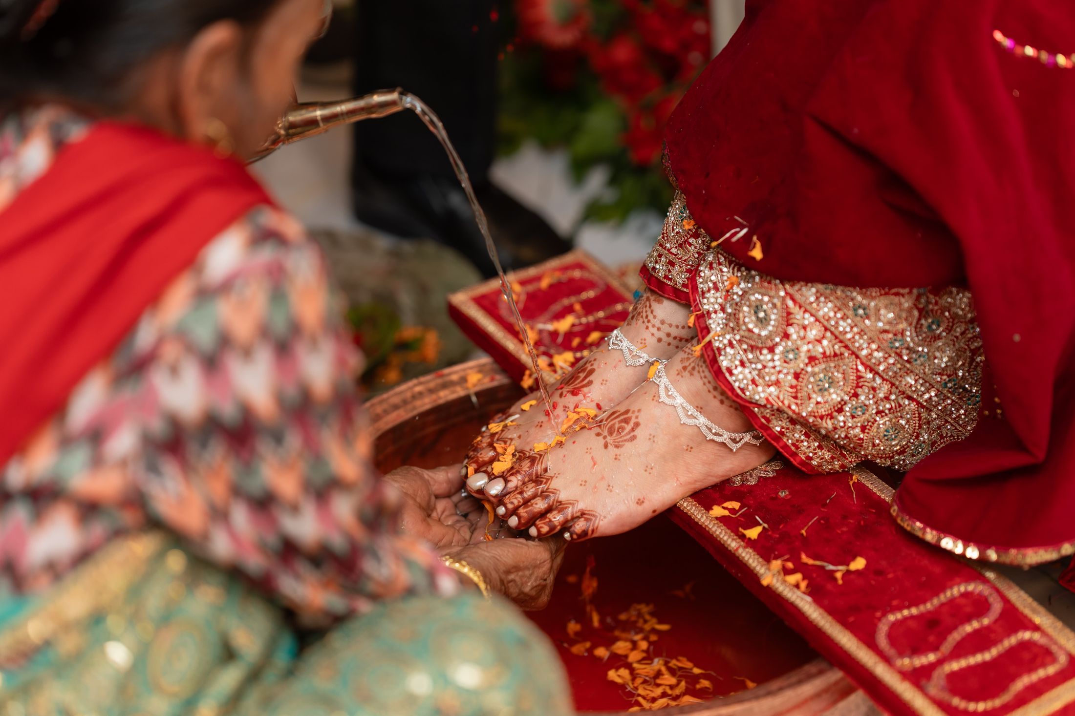 An older woman washing Inusha's henna-decorated feet during a wedding ritual