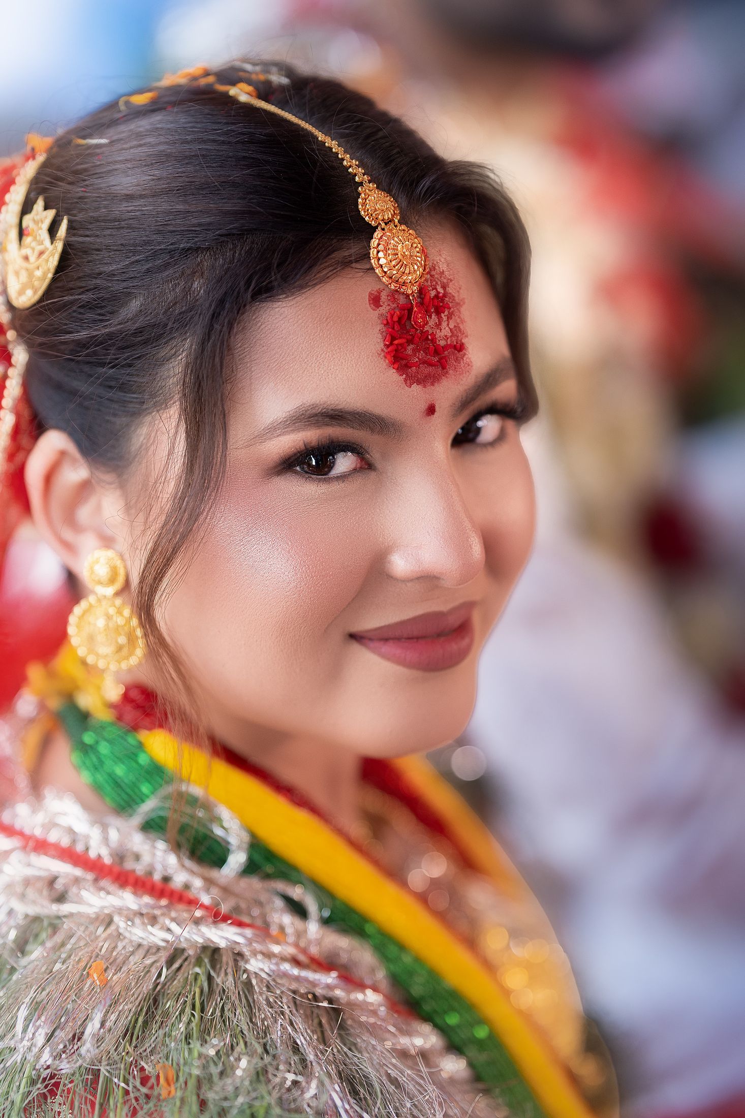 Close-up beauty portrait of Inusha with a red bindi, gold jewelry, and floral garland