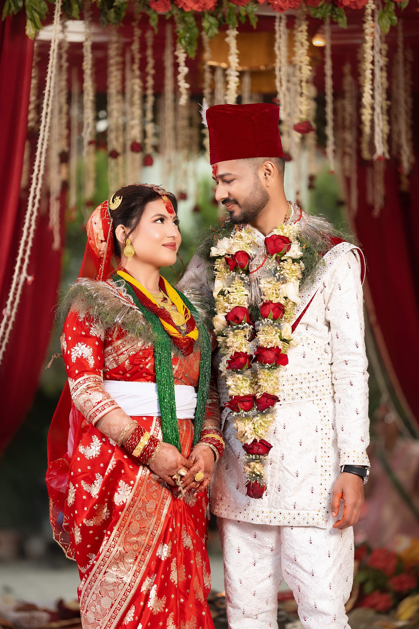 Inusha and Prashid standing together under a floral canopy, both wearing garlands