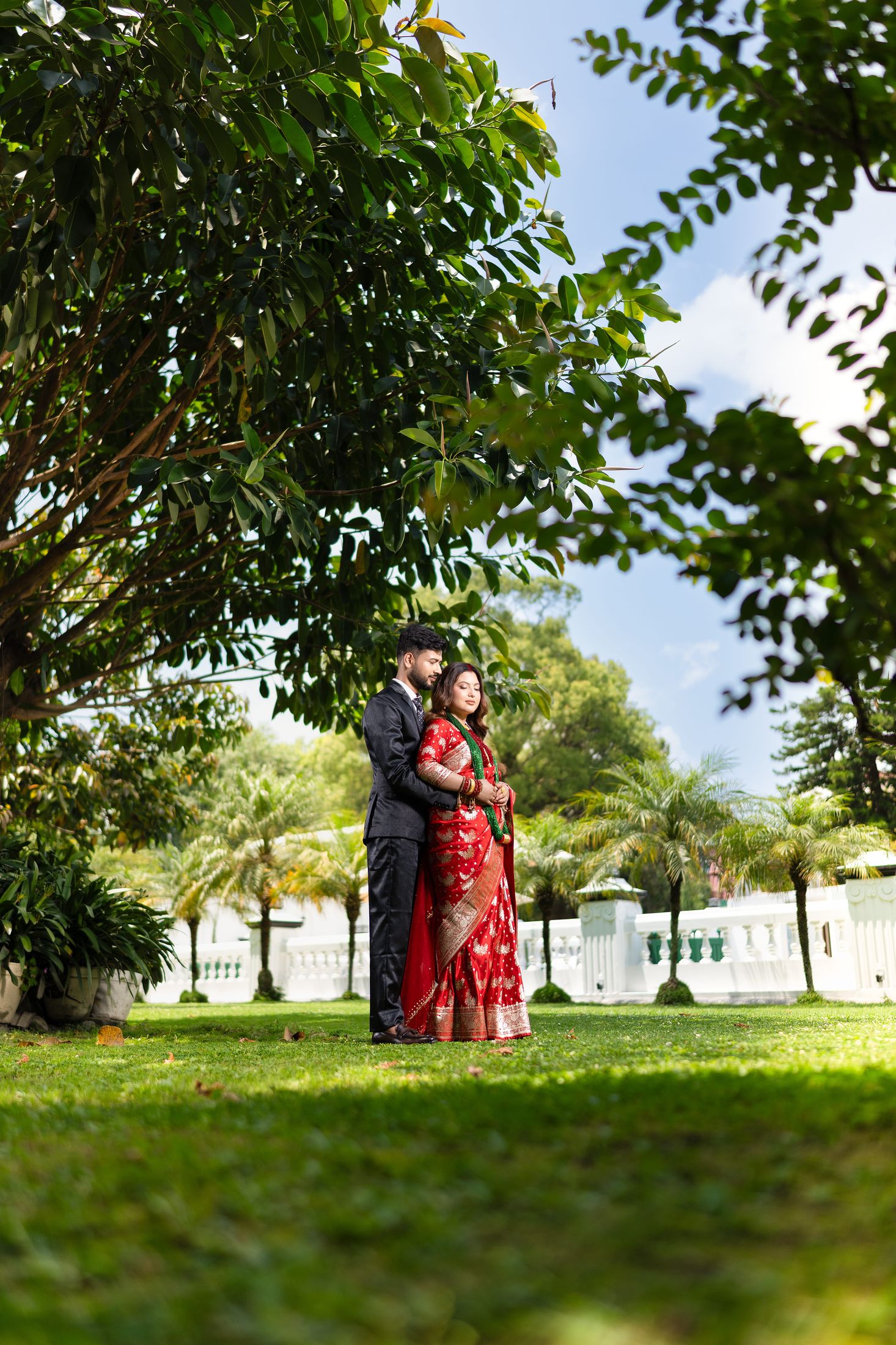 Inusha and Prashid standing together outdoors on a lawn under trees