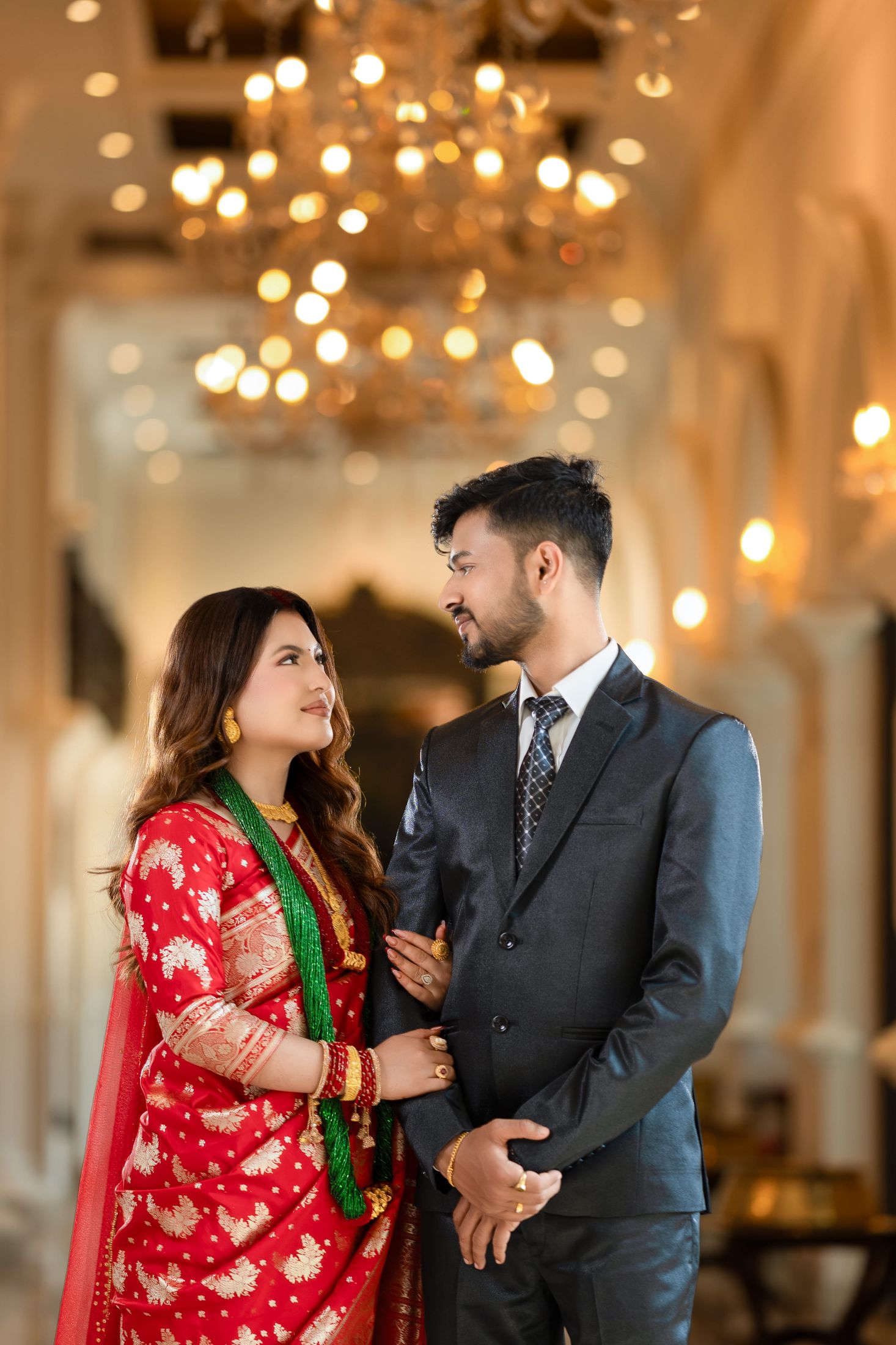 Inusha and Prashid standing close together in an elegant chandeliered venue