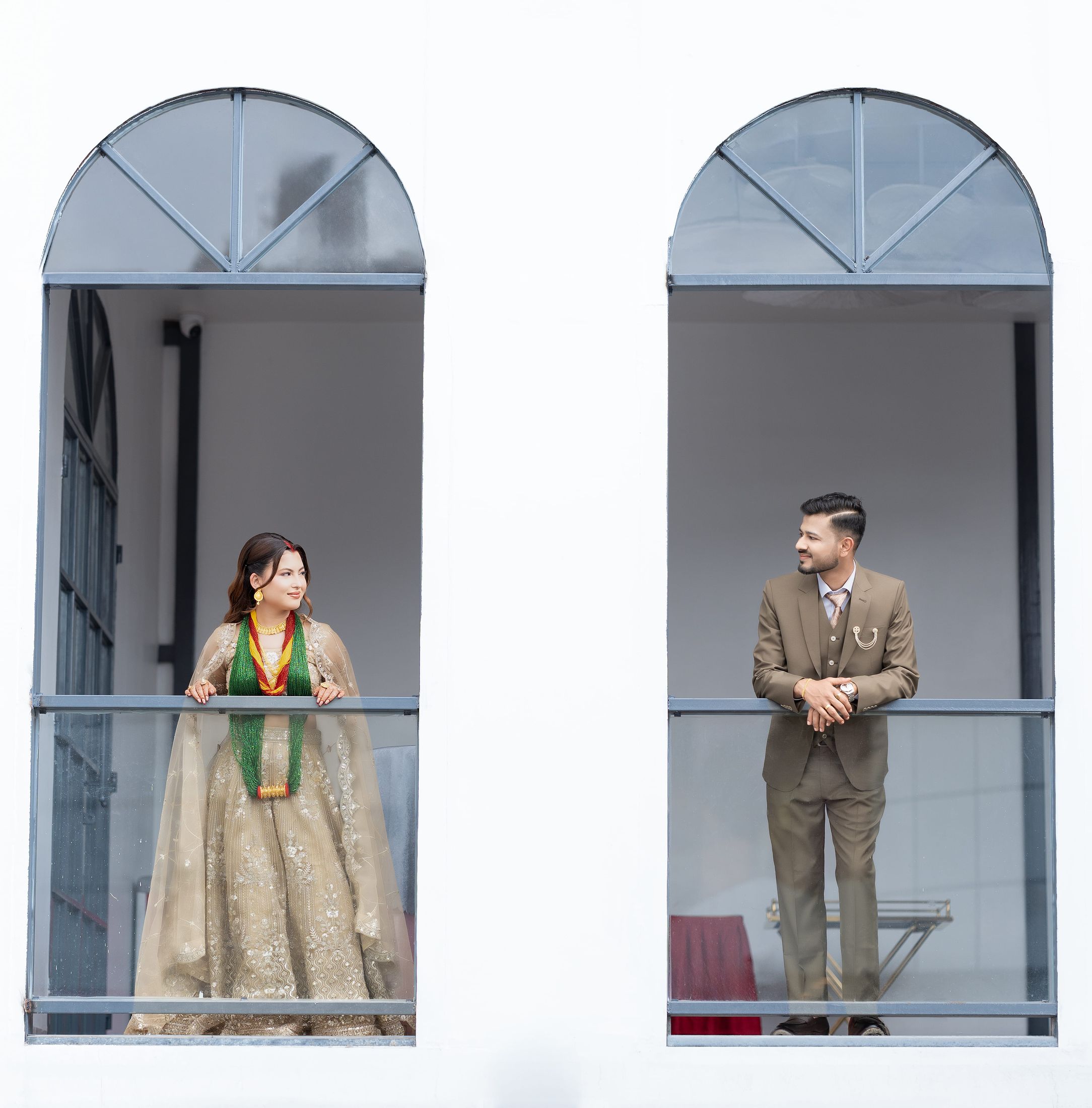 Symmetrical shot of Inusha and Prashid each standing in matching arched window frames