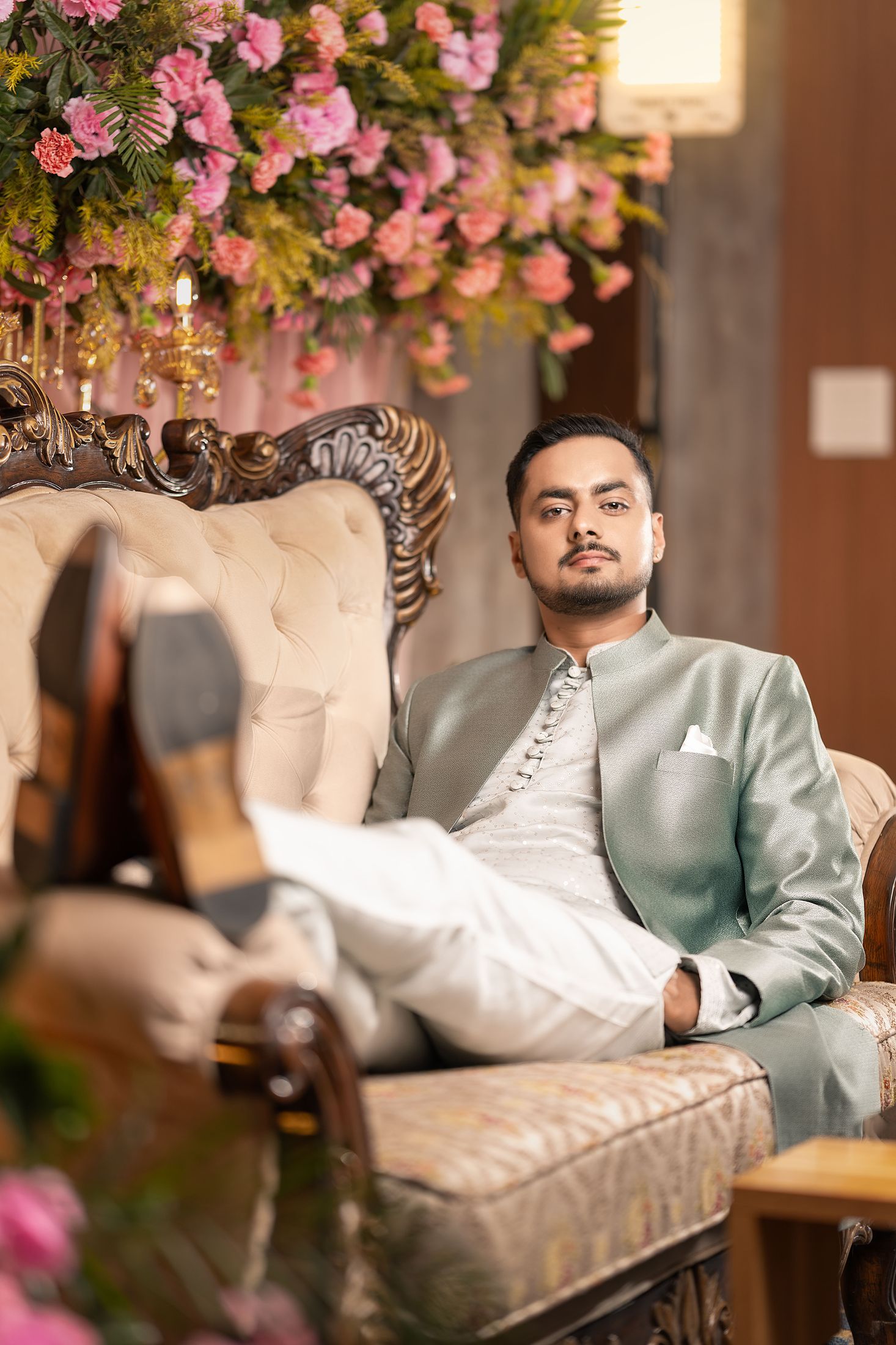 Nischal reclining sideways on a tufted studio couch with his legs crossed