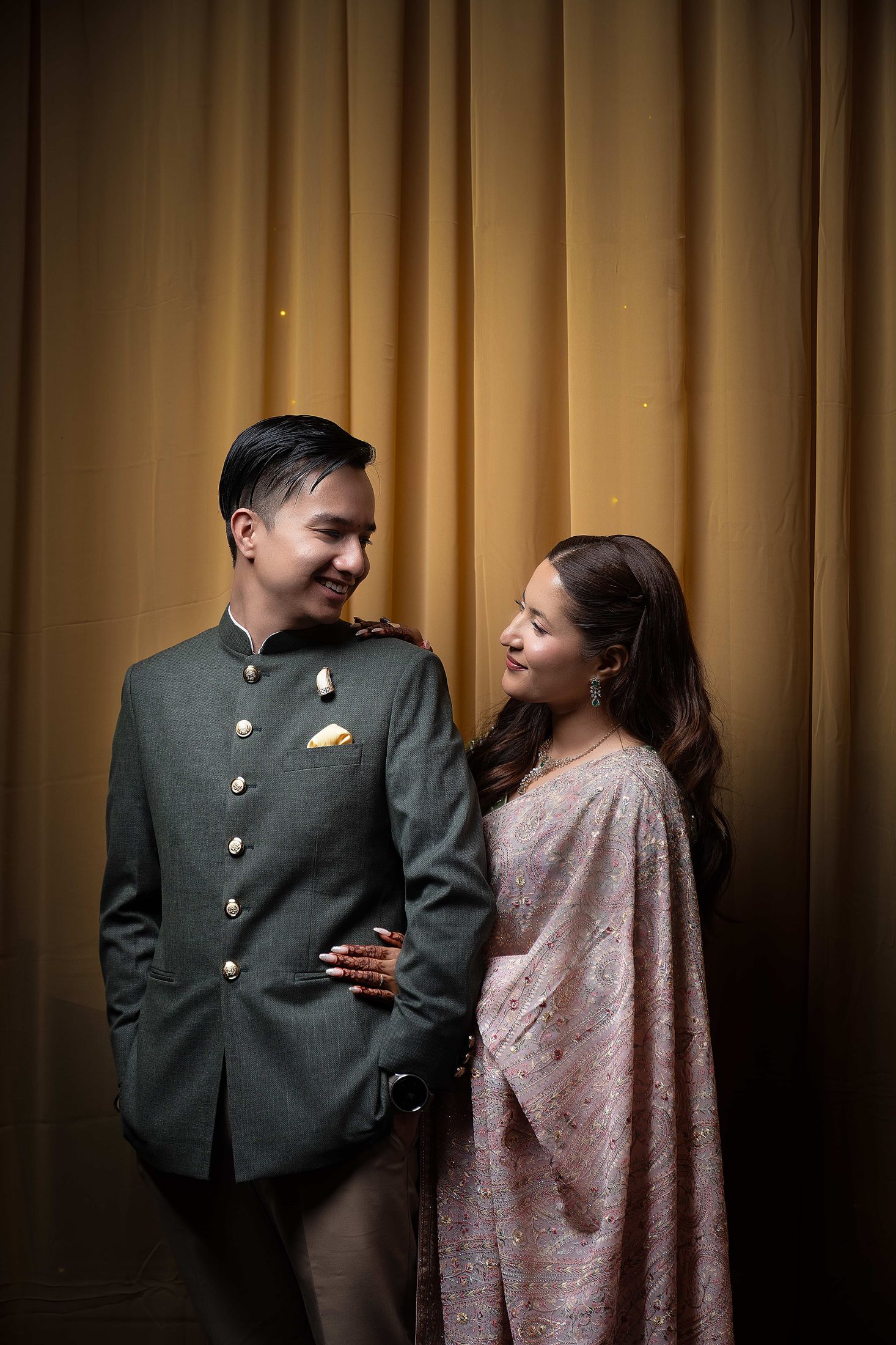 Shreya and Samagya standing together smiling against a golden curtain backdrop