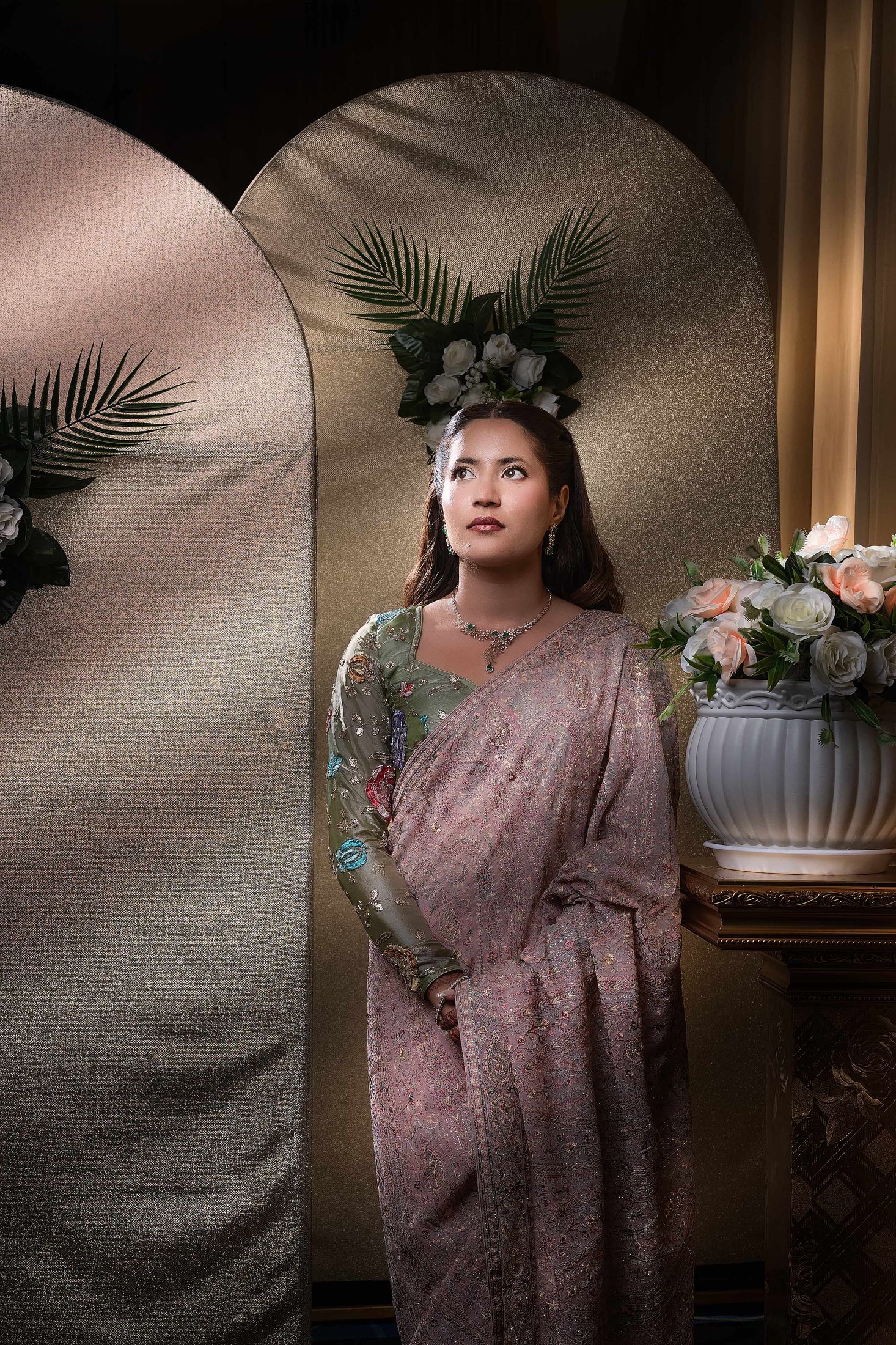 Shreya solo portrait against a gold arch backdrop decorated with flowers
