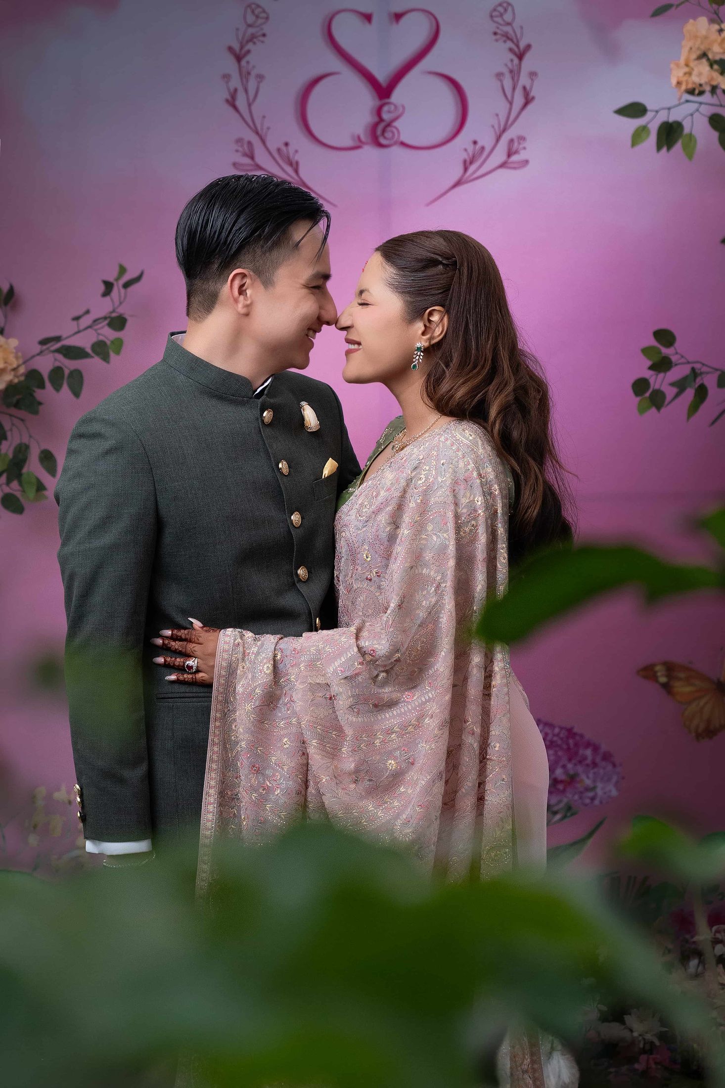 Shreya and Samagya smiling face to face against the same pink monogram backdrop